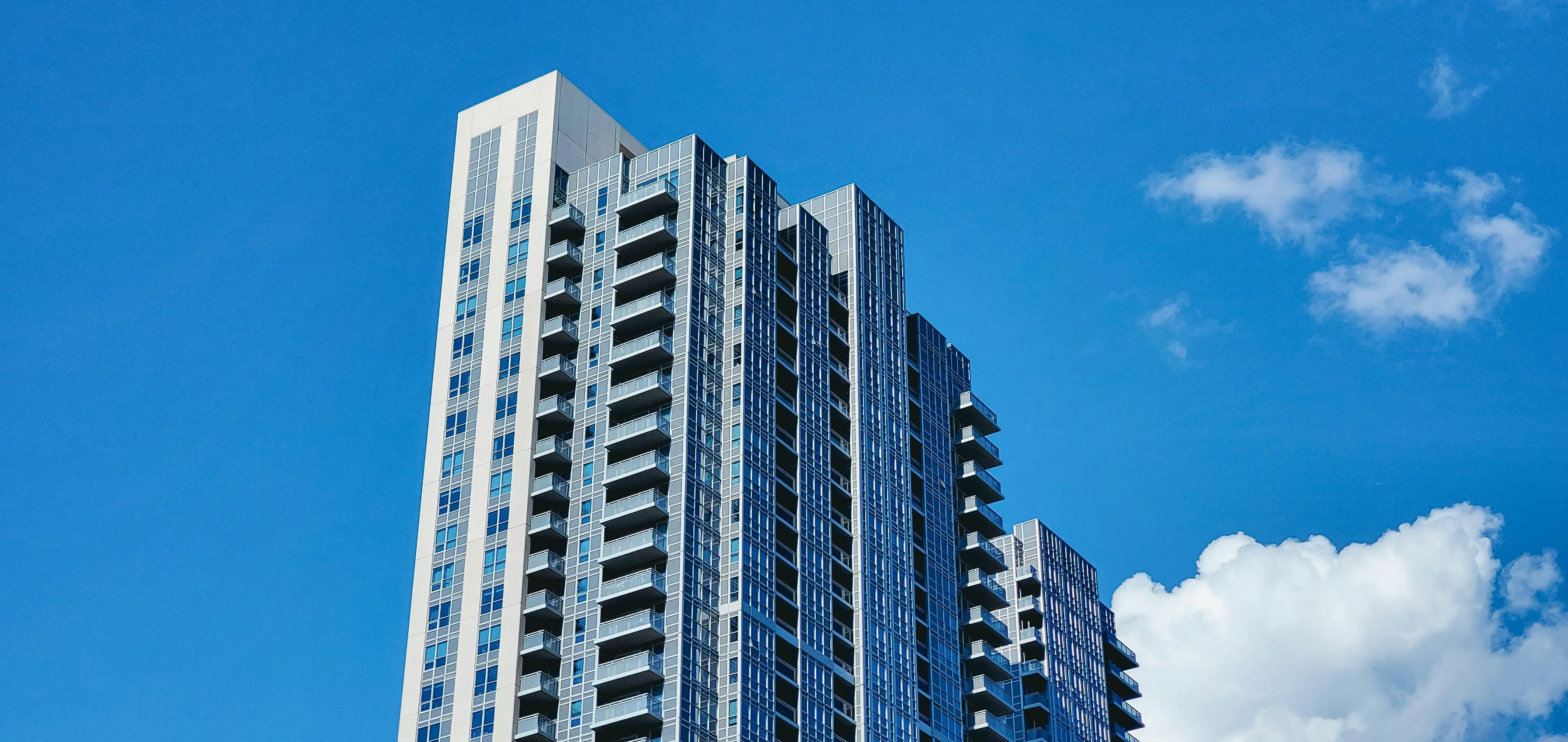 modern condo building with the daytime sky behind it.